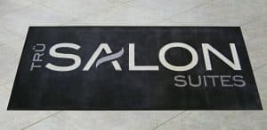 Floor mat on a tile floor with a large salon logo.